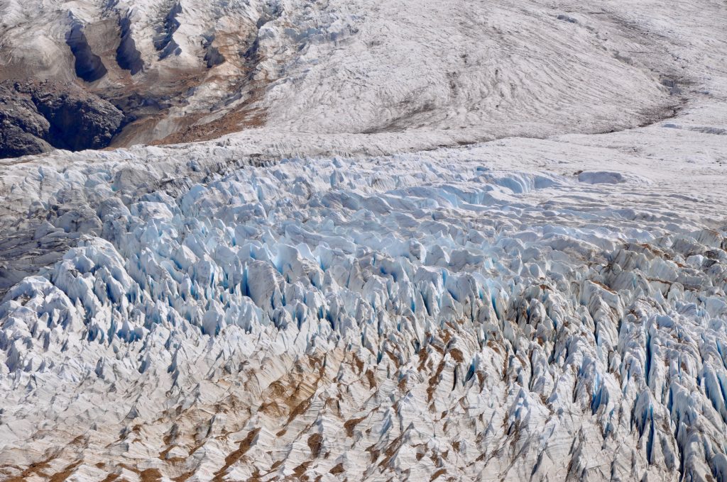 Nahaufnahme des Gletscher Grande mit feinen, blauen Gletscherspalten und aufgelagertem, braunem Sediment. 