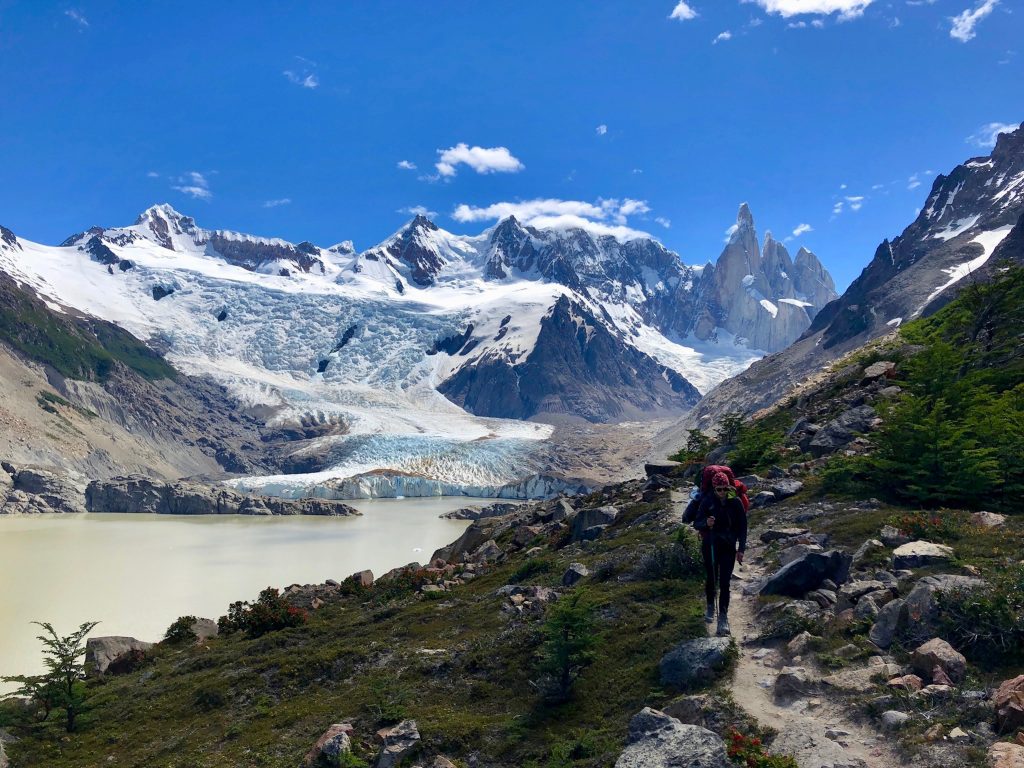 Charlotte vom Blog Rausgier mit Trekkingrucksack vor Gebirgspanorama mit Cerro Torre, Laguna Torre und Gletscher Grande.